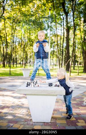 amusant garçon et fille jouant ensemble aux échecs dans le parc. Club d'échecs pour les enfants. Bonne enfance et amitié des enfants. Jeu logique pour le développement du cerveau. Drôle Banque D'Images