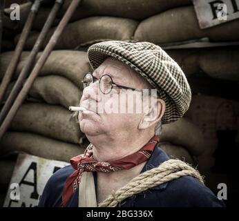 Gros plan d'un homme isolé vêtu d'un costume des années 1940 et d'une casquette plate en tant que gardien d'un ARP d'époque par l'abri de RAID aérien Severn Valley Railway, événement d'été des années 1940, au Royaume-Uni. Banque D'Images