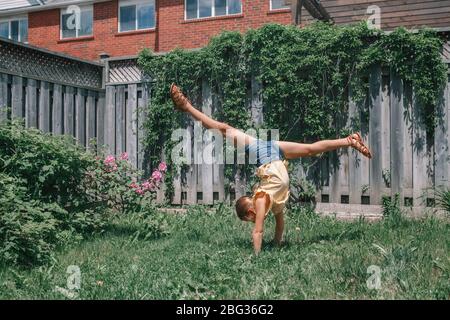 Drôle enfant adolescente faisant cartwheel à l'envers sur le stand. Joyeux gamin en plein air. Un style de vie heureux, l'esprit d'enfance et de liberté. Banque D'Images