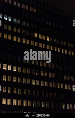 Façade d'un immeuble de bureaux moderne la nuit avec des fenêtres illuminées comme arrière-plan à Amsterdam, Pays-Bas Banque D'Images