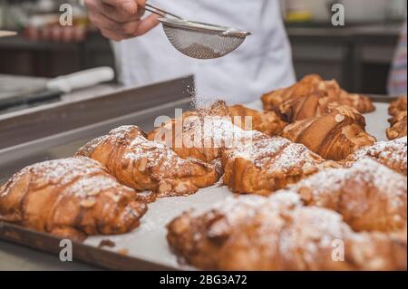 Croissants avec flocons d'amandes et sucre glace. Croissants sur une plaque de cuisson. Mise au point sur le premier plan. Banque D'Images