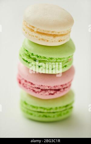 Gros plan vertical de délicieux macarons aux couleurs pastel empilés en ligne sur fond blanc Banque D'Images