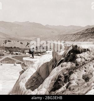 Mammoth Hot Springs terrasses travertin avec homme debout en 1900 avec Mammoth Springs Hotel à distance, Yellowstone, Montana, États-Unis Banque D'Images