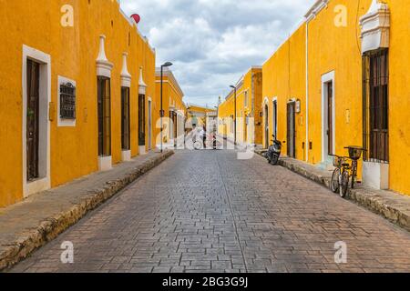 Paysage urbain avec des gens dans un Tricycle dans les rues jaunes colorées avec l'architecture de style colonial, Izamal, Mexique. Banque D'Images