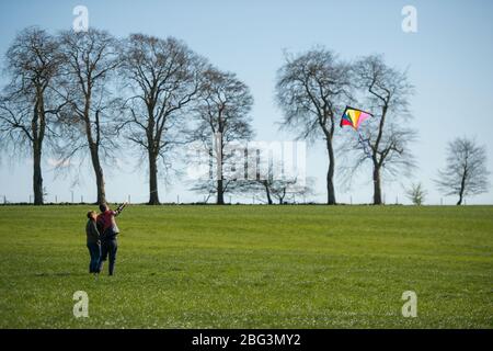 Bishopbriggs, Glasgow, Royaume-Uni. 20 avril 2020. Photo: Rachel et Scott utilisent leur temps d'exercice alloué et profiter d'une belle journée ensoleillée et venteuse pour voler leur cerf-volant. Un ciel bleu et un champ vert font un cadre parfait pour le vol en cerf-volant. Crédit : Colin Fisher/Alay Live News Banque D'Images