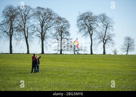 Bishopbriggs, Glasgow, Royaume-Uni. 20 avril 2020. Photo: Rachel et Scott utilisent leur temps d'exercice alloué et profiter d'une belle journée ensoleillée et venteuse pour voler leur cerf-volant. Un ciel bleu et un champ vert font un cadre parfait pour le vol en cerf-volant. Crédit : Colin Fisher/Alay Live News Banque D'Images