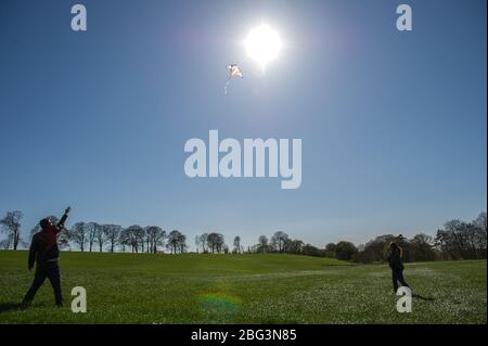 Bishopbriggs, Glasgow, Royaume-Uni. 20 avril 2020. Photo: Rachel et Scott utilisent leur temps d'exercice alloué et profiter d'une belle journée ensoleillée et venteuse pour voler leur cerf-volant. Un ciel bleu et un champ vert font un cadre parfait pour le vol en cerf-volant. Crédit : Colin Fisher/Alay Live News Banque D'Images