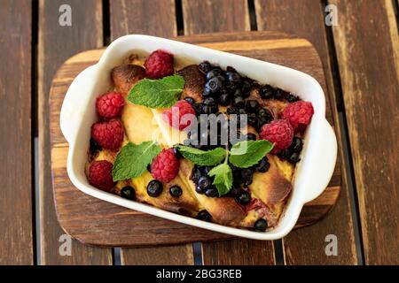 Crêpes au fromage cottage au milieu et sauce aux baies. Délicieux repas du petit déjeuner sur fond de bois. Dessert sucré de crêpes roulés à la framboise Banque D'Images
