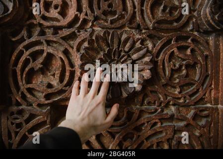 La main de l'homme touche une porte ornée, fort rouge, Delhi, Inde Banque D'Images