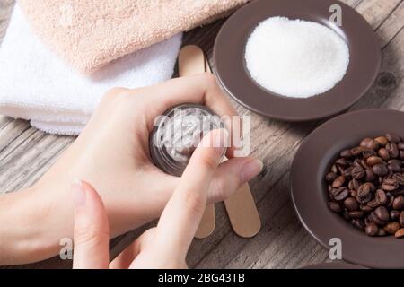 Une femme applique du café fait maison frottez. SPA, beauté. Ingrédients pour la confection d'un gommage, de grains de café, de sucre, de crème. Soins de la peau. Hydratant, exfoliati Banque D'Images