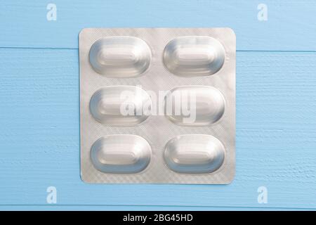 Blister de comprimés médicaux sur fond bleu en bois. Le concept de traitement alternatif pour le coronavirus Banque D'Images