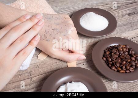 Une femme applique du café fait maison frottez sur sa main. SPA, beauté. Ingrédients pour la confection d'un gommage, de grains de café, de sucre, de crème. Soins de la peau. Hydratant Banque D'Images