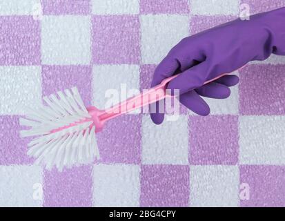 Brosse toilette à la main sur fond de mur de carrelage Banque D'Images