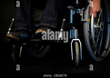 Un gros plan de la main d'un utilisateur de fauteuil roulant, à l'aide de sa main pour déplacer le fauteuil roulant. Banque D'Images