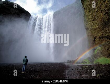 Homme debout devant la cascade de Skogarfoss en Islande Banque D'Images