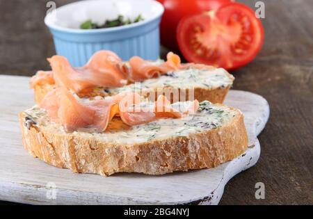 Sandwichs au poisson à bord de la planche à découper sur une table en bois Banque D'Images