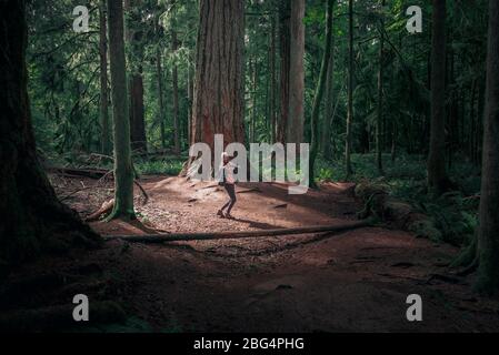 Femme regardant en arrière souriant et montrant avec le doigt dans la forêt MacMillan Banque D'Images