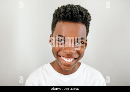 Photo d'un jeune garçon de la préadolescence noir souriant portant un t-shirt blanc Banque D'Images