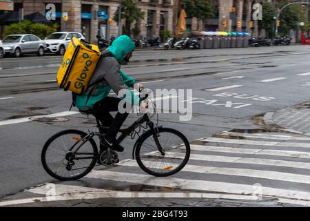 Barcelone, Espagne. 20 avril 2020. Glovo livyman à vélo dans les rues vides de Barcelone sous la pluie Banque D'Images