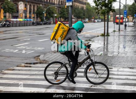 Barcelone, Espagne. 20 avril 2020. Glovo livyman à vélo dans les rues vides de Barcelone sous la pluie Banque D'Images