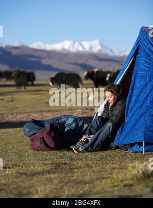 Femme mettant ses bottes au camp au Tibet Banque D'Images