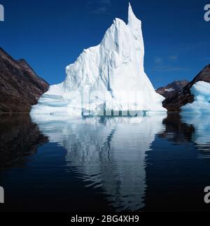 Iceberg flottant dans le fjord fixe de l'est du Groenland Banque D'Images