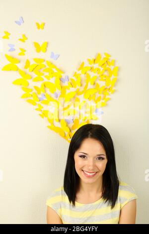 Fille près de papillons en papier voler sur le mur Banque D'Images