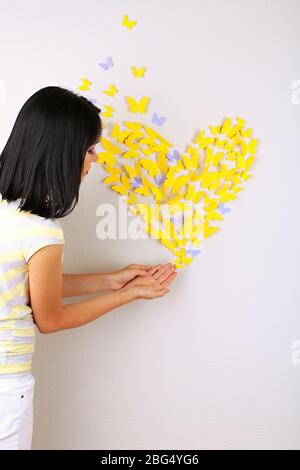 Fille près de papillons en papier voler sur le mur Banque D'Images