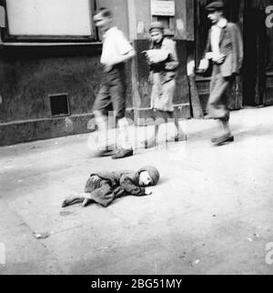 Documentaire de la seconde Guerre mondiale. Un enfant affamé allongé sur la rue du ghetto de Varsovie, photographié par un sergent dans les forces armées allemandes, vers 1941. Banque D'Images