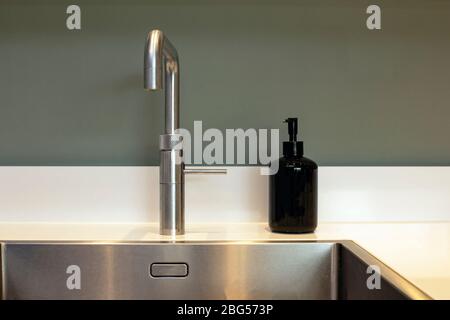 Lavabo de cuisine propre et distributeur de savon de conception moderne avec mur gris Banque D'Images