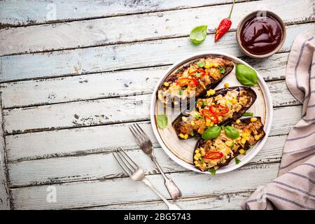 Bateaux d'aubergines cuits au four, farcis de viande hachée, tomates, maïs, ail et fromage en plaque blanche, vue de dessus Banque D'Images