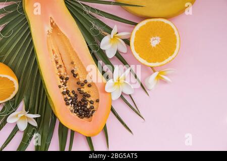 Composition créative avec feuilles de palmier, papaye et fleurs de plumeria. Banque D'Images