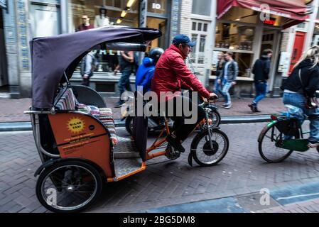 Amsterdam, Pays-Bas - 7 septembre 2018: L'homme en vélo de taxi pousse-pousse circule et les gens marchent dans un vieux centre historique d'Amsterdam, Netherlan Banque D'Images