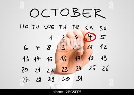 Homme qui sonne la Journée mondiale de l'animal, samedi 4 octobre, en rouge sur un calendrier manuscrit sur une interface virtuelle comme rappel de son importation Banque D'Images