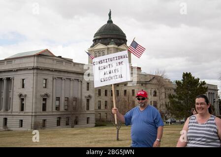 Helena, Montana - 19 avril 2020: Les hommes protestant font de l'Amérique un grand chapeau de nouveau détenant des droits constitutionnels sont des signes essentiels à une organisation de protestation Banque D'Images