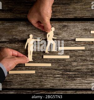 Concept de travail d'équipe avec les mains de deux hommes d'affaires soutenant les coupures de papier avec une personne donnant une impulsion de soutien de derrière et de l'ot Banque D'Images