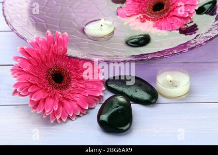 Pierres de spa, belles fleurs de gerbera et bougies sur l'eau Banque D'Images