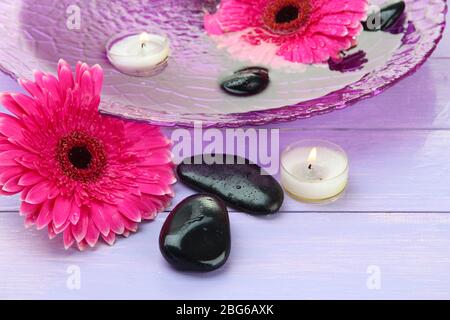 Pierres de spa, belles fleurs de gerbera et bougies sur l'eau Banque D'Images