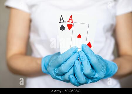 Jeune femme avec des gants de protection jetables tenant des cartes - paire d'as Banque D'Images