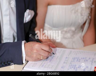 Le marié met sa signature dans le document du mariage, point de mire sélectif Banque D'Images