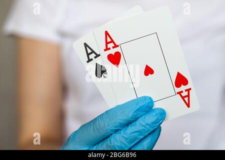 Jeune femme avec des gants de protection jetables tenant des cartes - paire d'as Banque D'Images