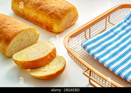 Un pain blanc fait maison sur un rack de refroidissement avec un chiffon sur une table blanche Banque D'Images