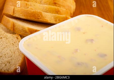 Pain de blé en tranches et fromage fondu dans un plateau en plastique sur un plateau de découpe en bois. Gros plan Banque D'Images