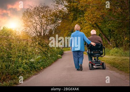 Les vieux aînés mûrs se sont mariés avec plaisir à un couple dehors dans la campagne alors que l'on conduit un scooter motorisé de mobilité. Concept de soignant de la santé Banque D'Images