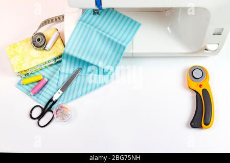 il y a des outils de courtepointes sur la table. couteau à patchwork, ciseaux, tapis de découpe doublé, auto-verrouillage, fils, ruban de mesure, machine à coudre. espace de copie Banque D'Images