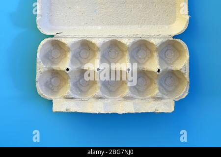Vue supérieure du plateau en carton vide. Plateau à œufs sur fond bleu. Bac gris papier sans œufs. Banque D'Images