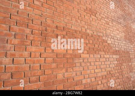 Mur de briques, vue inclinée, éclairé par une lumière chaude. Banque D'Images