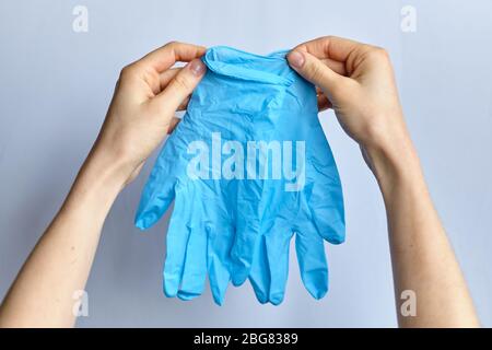 La main tient des gants de protection médicale sur un fond blanc. Gros plan. Banque D'Images