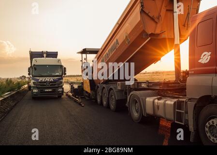 travailleurs de la construction de routes qui travaillent sur des chaussées. entretien des routes, machine d'asphalte qui pond de nouveaux asphalte ou bitume lors de la construction de routes Banque D'Images