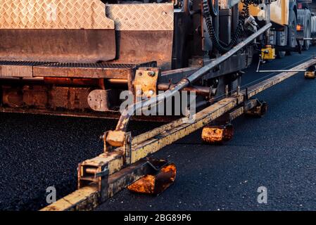 travailleurs de la construction de routes qui travaillent sur des chaussées. entretien des routes, machine d'asphalte qui pond de nouveaux asphalte ou bitume lors de la construction de routes Banque D'Images